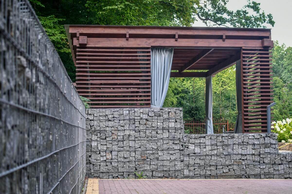 Wooden garden blinds screen the stone-walled gazebo.