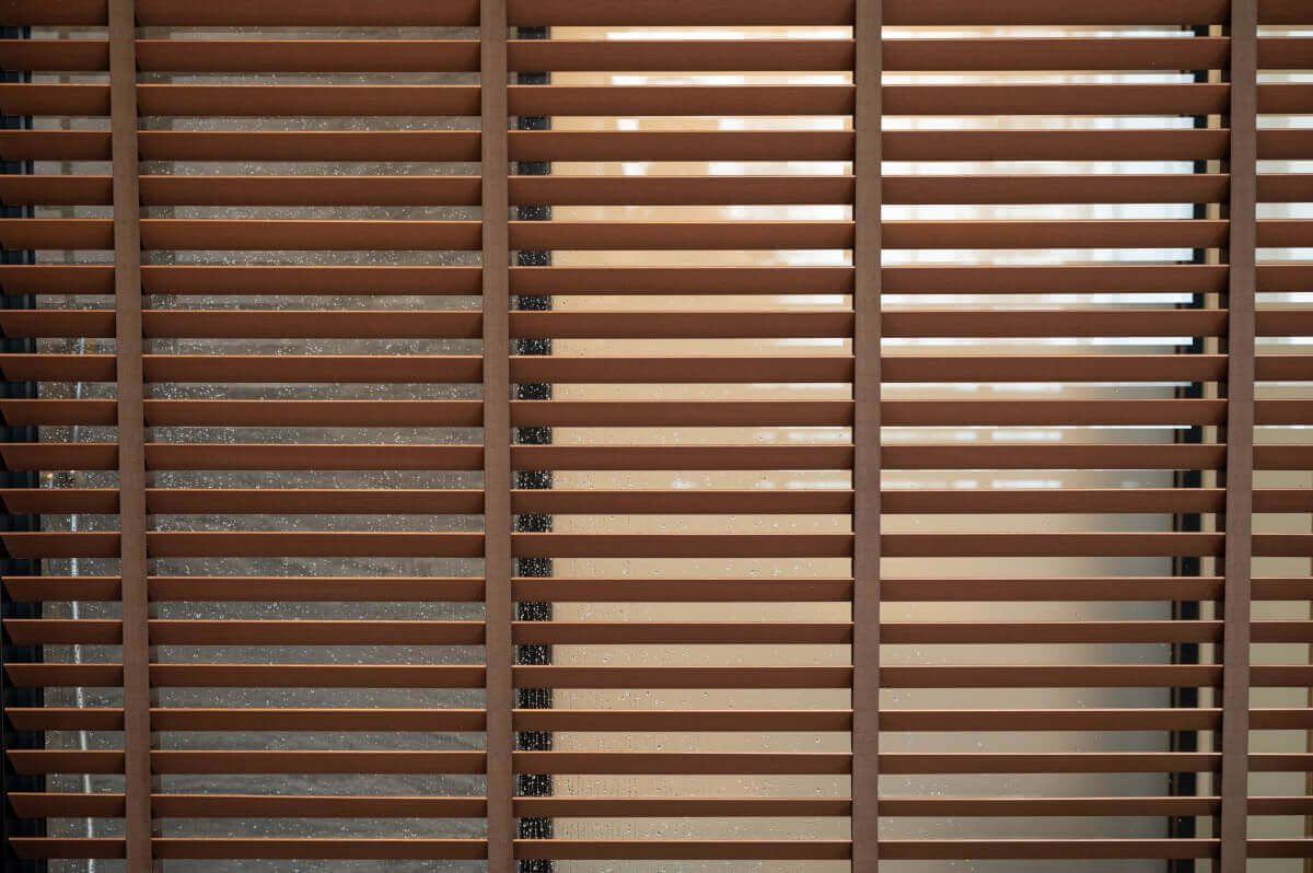 Wooden movable blinds mounted against the window background.
