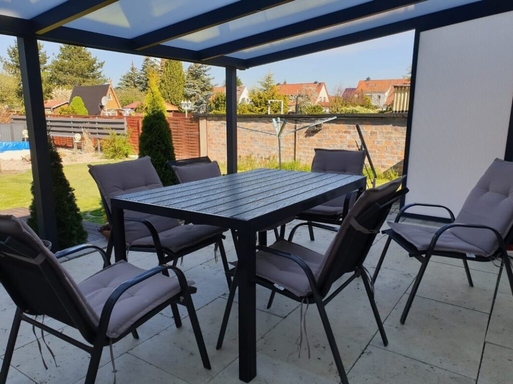 Zadaszenia lamelowe zapewniają ochronę nad przytulnym zestawem mebli ogrodowych.